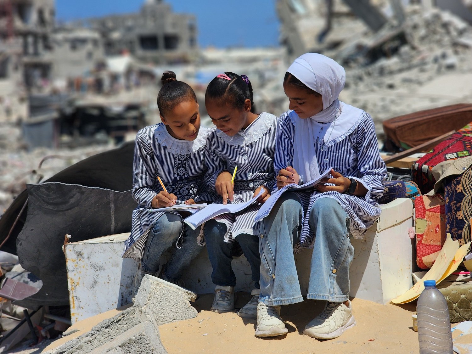 KHAN YUNIS, GAZA - SEPTEMBER 03: Students do homeworks after the lessons at their tent school, in which their teacher Alaa Abu Mustafa, whose house was destroyed in the Israeli army's attacks, gives them education in Khan Yunis, Gaza on September 03, 2024. The tent school was built on the rubble of the destroyed house of the teacher. Despite the limited and difficult conditions, teacher Alaa strives to ensure that primary school students are not deprived of education. ( Hani Alshaer - Anadolu Agency )