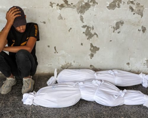 EDITORS NOTE: Graphic content / TOPSHOT - A boy reacts as he sits by the shrouded bodies of children killed in overnight Israeli bombardment, at the Ahli Arab hospital in Gaza City on October 2, 2024 amid the ongoing war in the Palestinian territory between Israel and Hamas. (Photo by Omar AL-QATTAA / AFP)