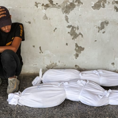 EDITORS NOTE: Graphic content / TOPSHOT - A boy reacts as he sits by the shrouded bodies of children killed in overnight Israeli bombardment, at the Ahli Arab hospital in Gaza City on October 2, 2024 amid the ongoing war in the Palestinian territory between Israel and Hamas. (Photo by Omar AL-QATTAA / AFP)
